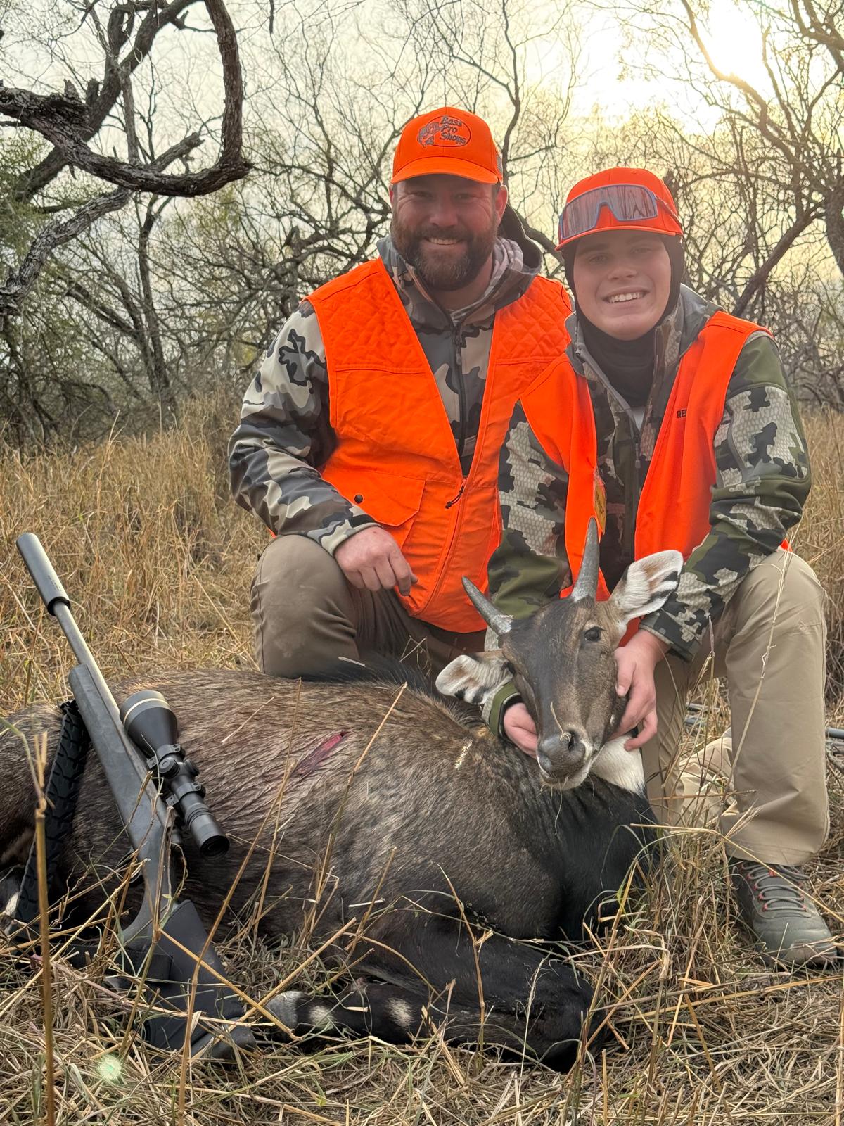 An adult and young hunter smiling together after a hunt