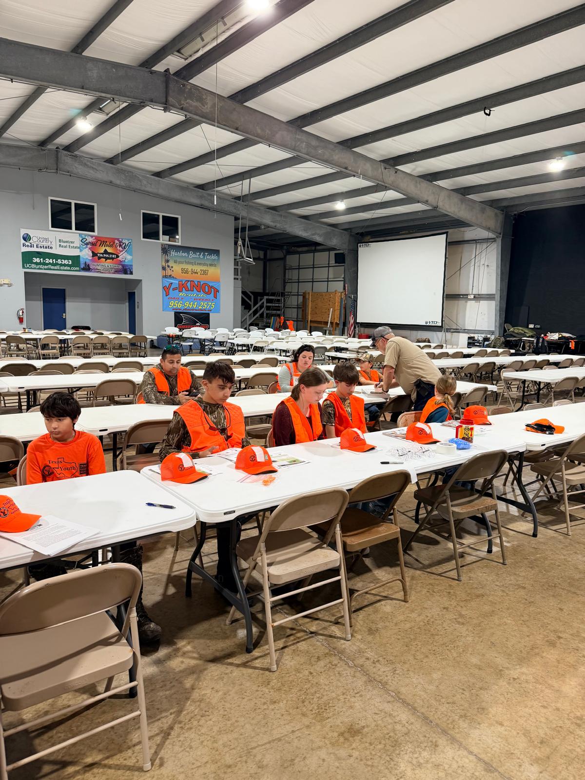 Young people and adults reviewing materials at tables before a hunt