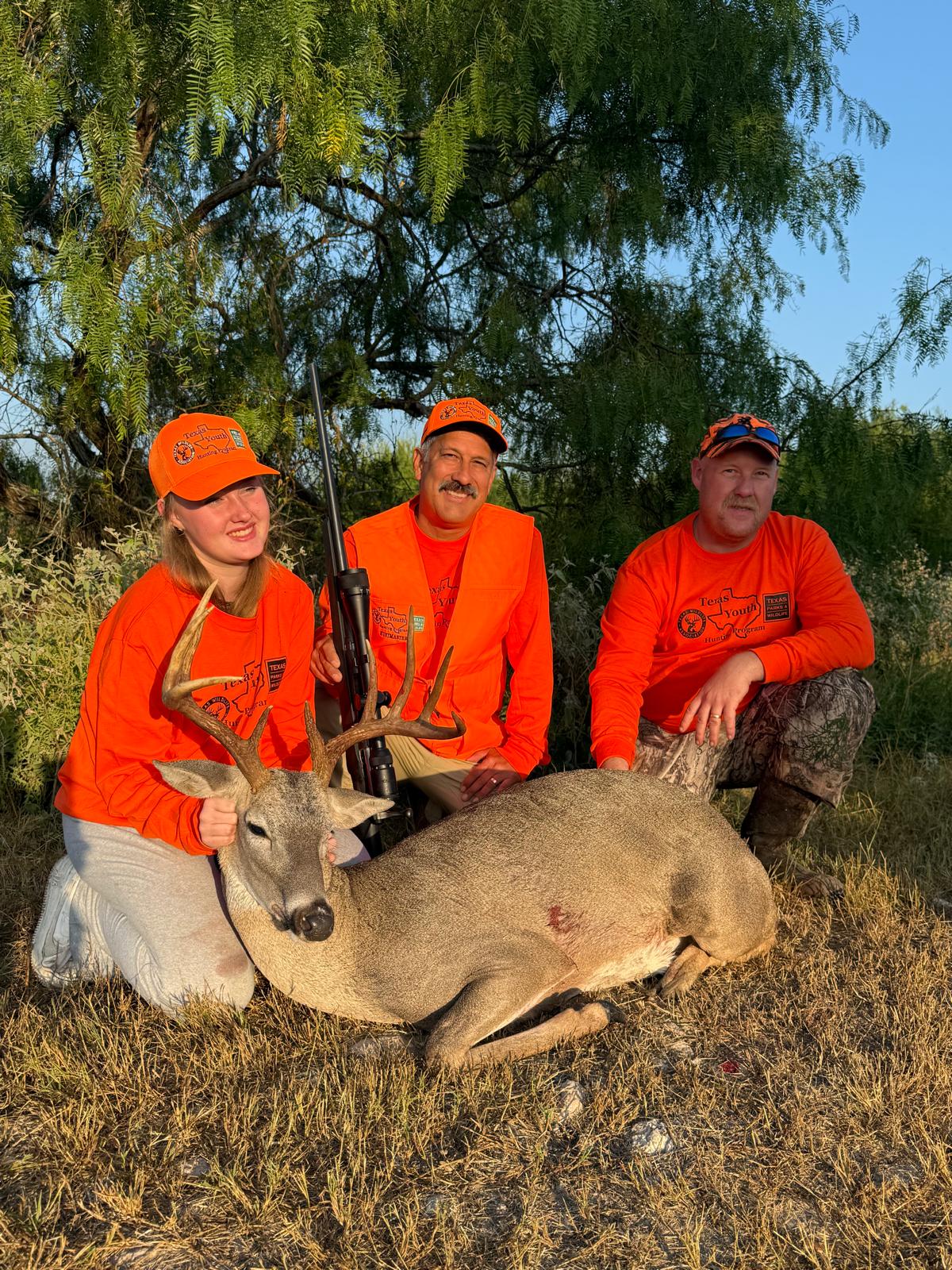 A young hunter and two adults with a harvested whitetail buck